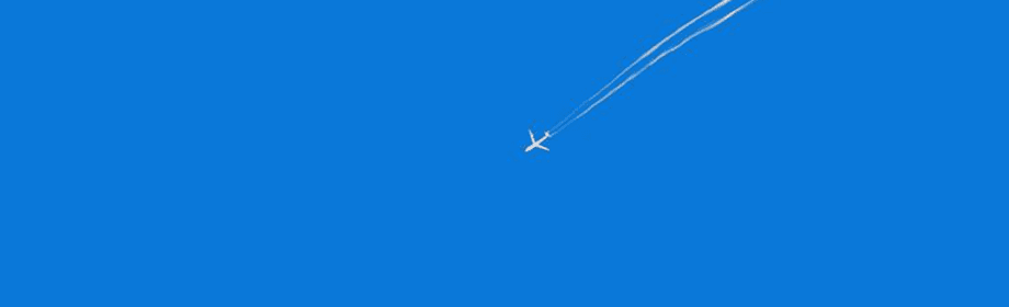 An airplane high in a clear blue sky, trailing two long white contrails